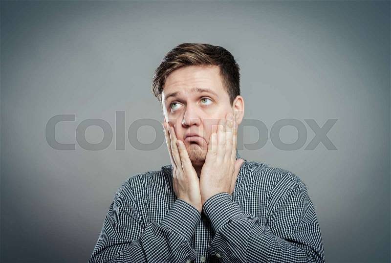 A young man dragging face down with hands, stock photo
