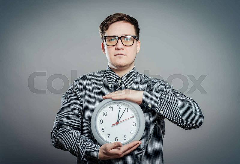 Young Man Holding A Clock On Gray Background, stock photo