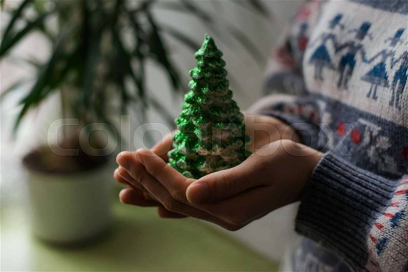 Hands hold a christmas candle as fur-tree form, stock photo