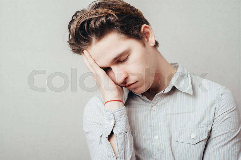 Young Man wants to sleep. Put his head in his hands, stock photo