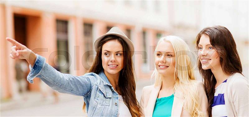 Holidays and tourism concept - beautiful girls looking for direction in the city, stock photo