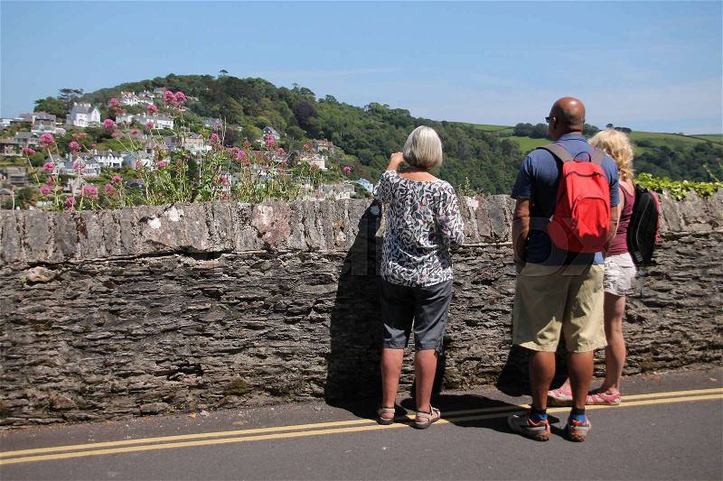The lady tells the tourists a story about Dartmouth in England in the summer, stock photo