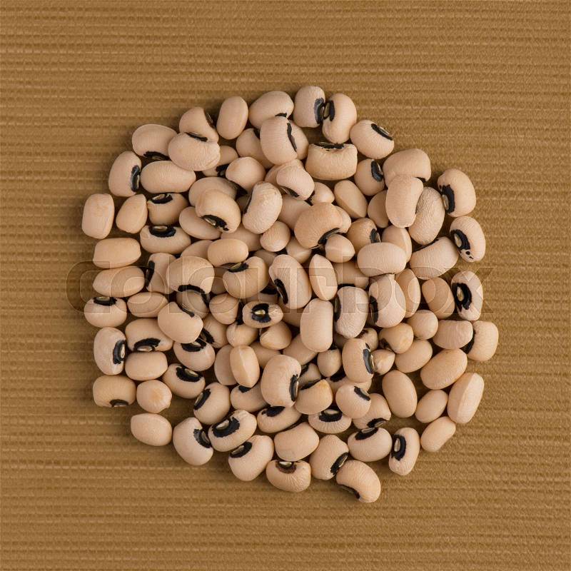 Top view of circle of white beans against brown vinyl background, stock photo