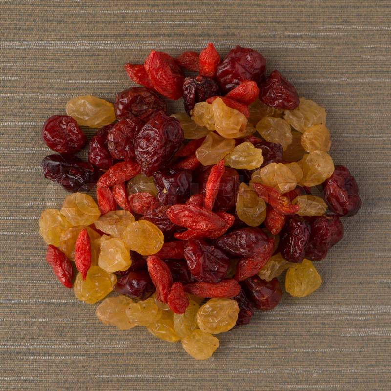 Top view of circle of mixed dried fruits against green vinyl background, stock photo