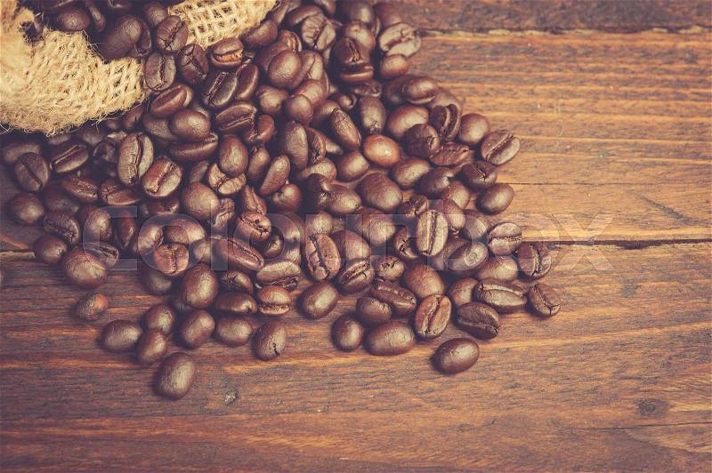Coffee beans on wooden table,vintage color toned image, stock photo