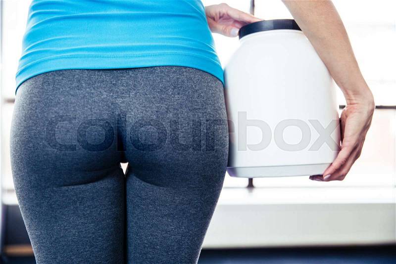 Back view portrait of female body with sports nutrition at gym, stock photo