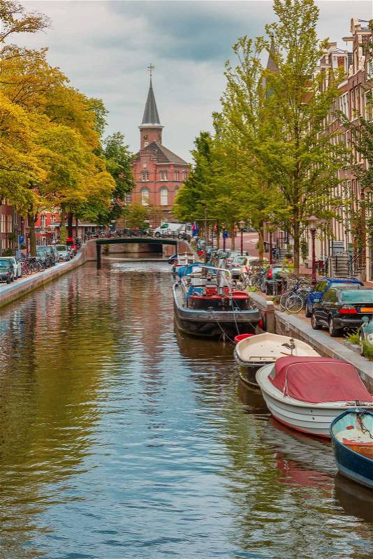City view of Amsterdam canal, church and typical houses, boats and bicycles, Holland, Netherlands, stock photo