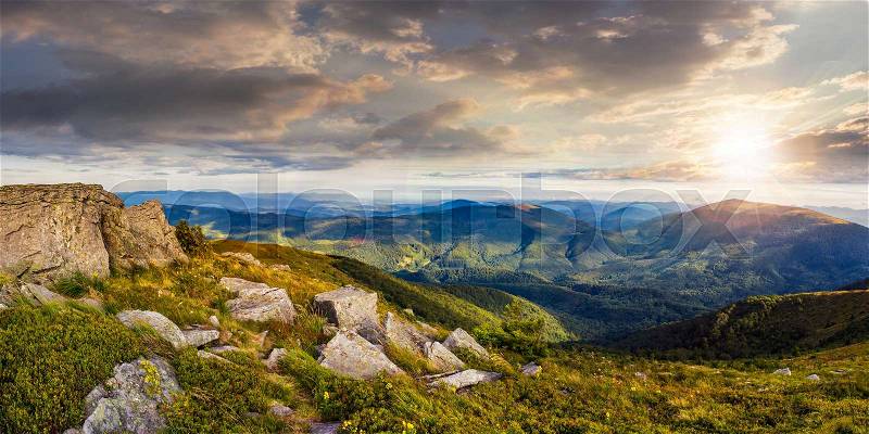 Panoranic mountain landscape. valley with stones in grass on top of the hillside of mountain range in sunset light, stock photo
