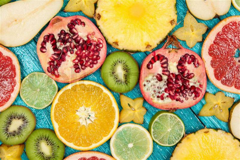 Colorful fruit slices on blue wooden surface, stock photo