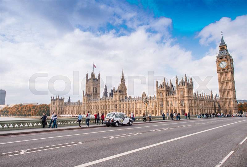 LONDON - SEPTEMBER 29, 2013: Tourists walk along Westminster Bridge. The city is visited by more than 30 million people annually, stock photo