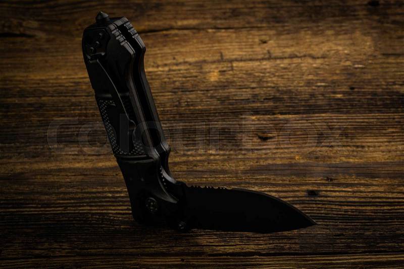 Folding pocket knife with one edge on wooden background, stock photo