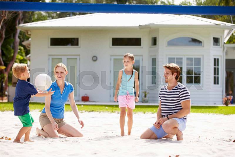 Family Playing Game Of Volleyball In Garden, stock photo