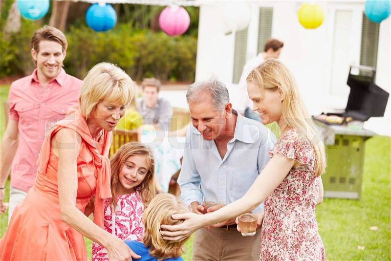 Multi Generation Family Enjoying Meal In Garden Together, stock photo