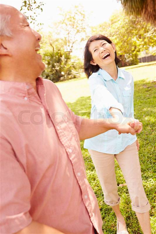 Senior Asian Couple Walking Through Park Together, stock photo