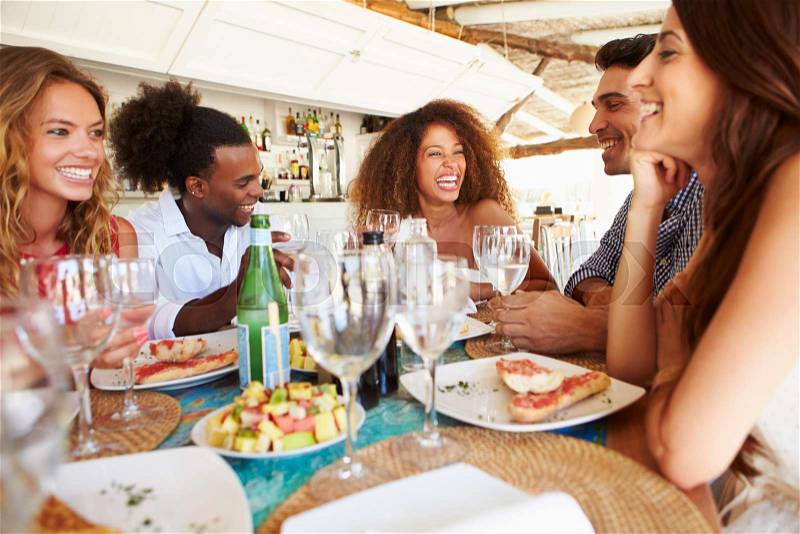 Group Of Young Friends Enjoying Meal In Outdoor Restaurant, stock photo