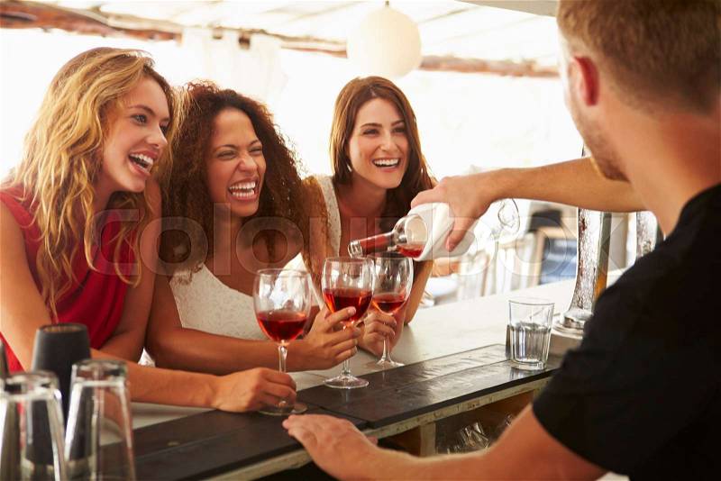 Three Female Friends Enjoying Drink At Outdoor Bar, stock photo
