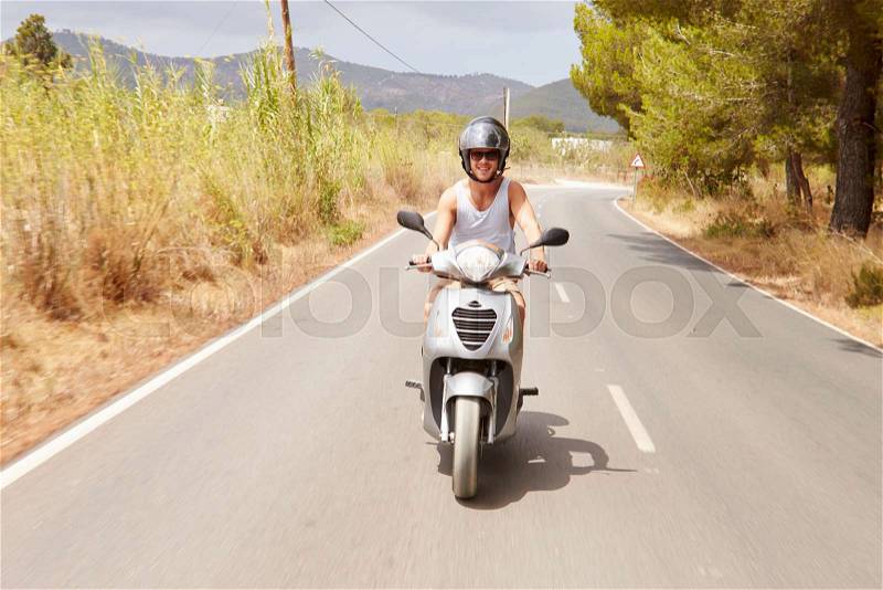 Young Man Riding Motor Scooter Along Country Road, stock photo