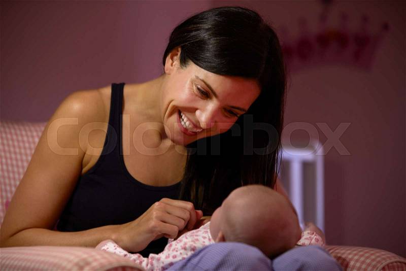 Mother At Home Cuddling Newborn Baby In Nursery, stock photo