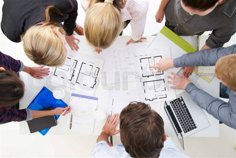 Overhead View Of Architects Discussing Plans In Office, stock photo