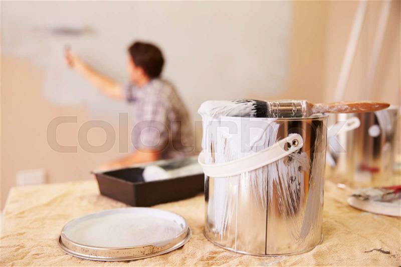 Man Decorating Room Using Paint Roller On Wall, stock photo