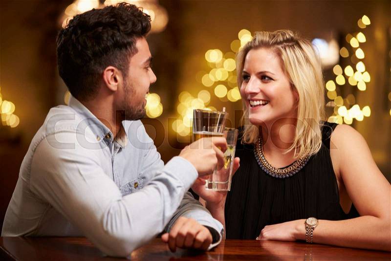 Couple Enjoying Evening Drinks In Bar, stock photo