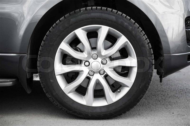 Modern automotive wheel on gray light alloy disc, stock photo