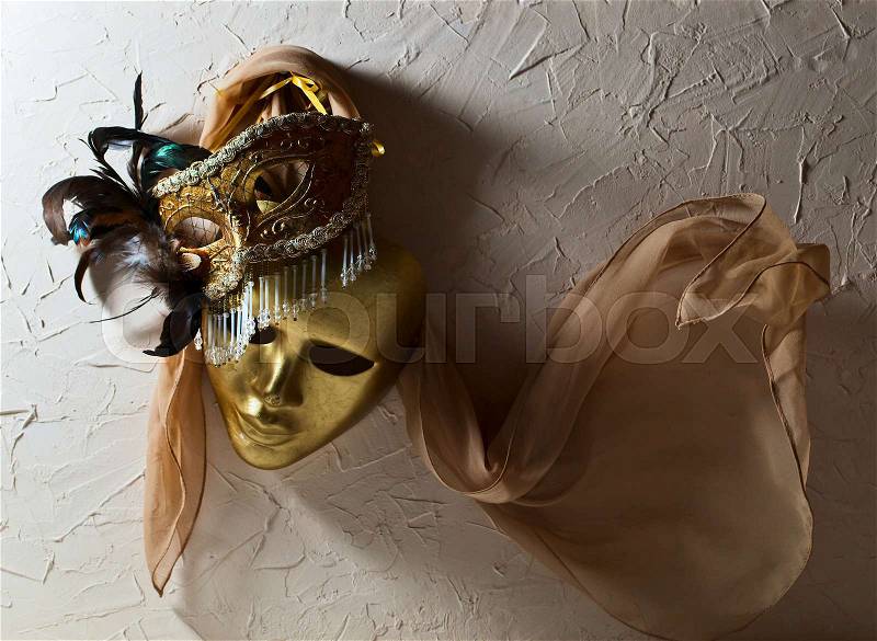 Two golden Venetian masks on old wall, stock photo