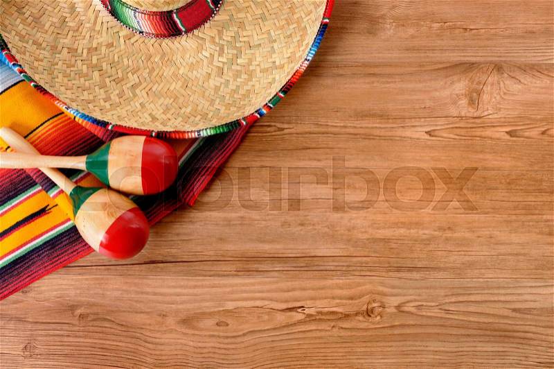Mexican background with sombrero straw hat, maracas and traditional serape blanket or rug on a wood floor. Space for copy, stock photo