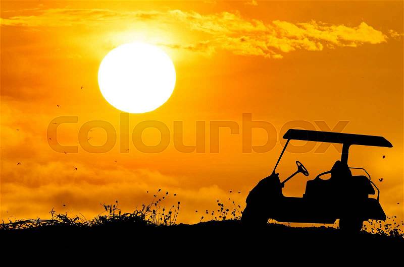 Golf cart on grass silhouettes background with sun set, stock photo