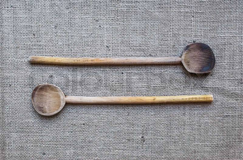 Two rustic wood cooking spoons over a sackcloth background, stock photo