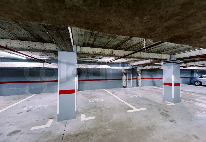 Empty underground car park with a solitaire car in the right corner, stock photo