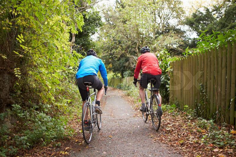 Two Mature Male Cyclists Riding Bikes Along Path, stock photo