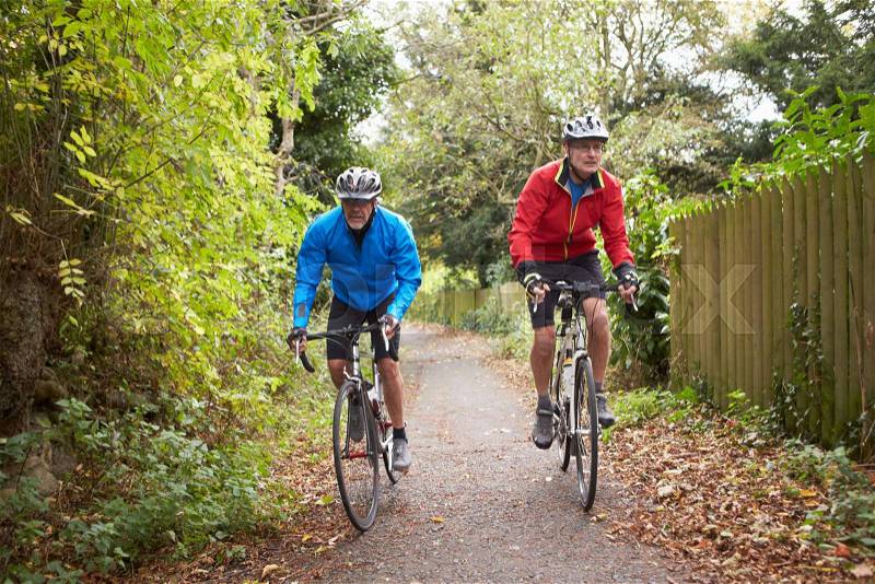 Two Mature Male Cyclists Riding Bikes Along Path, stock photo
