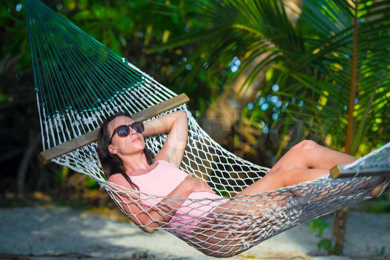 Woman in swimsuit relaxing on hammock sunbathing on vacation, stock photo