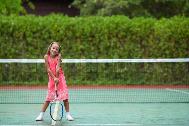 Little girl playing tennis on the court on vacation, stock photo