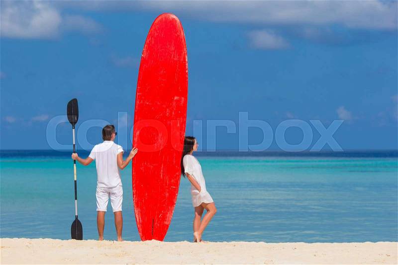 Young happy couple with red surfboard during tropical vacation, stock photo