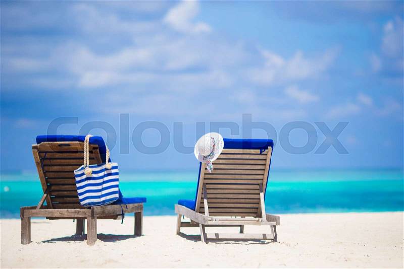 Lounge chairs with stripe bag and hat on tropical beach at Maldives, stock photo