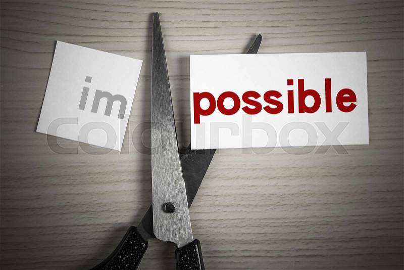A scissor is cuting possible from impossible on the desk, stock photo