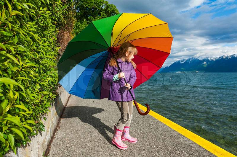 Outdoor portrait of a cute little girl, wearing rain jacket and boots, stock photo