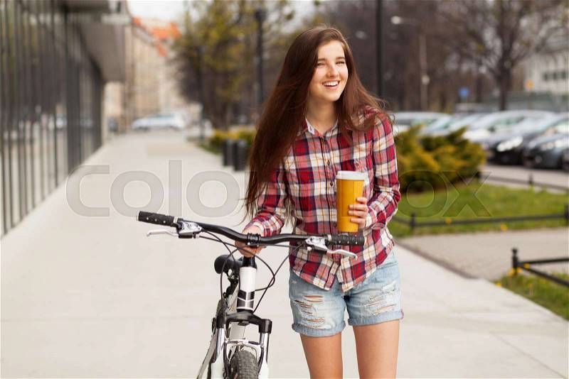 Young beautiful woman with coffee cup and a bicycle, stock photo