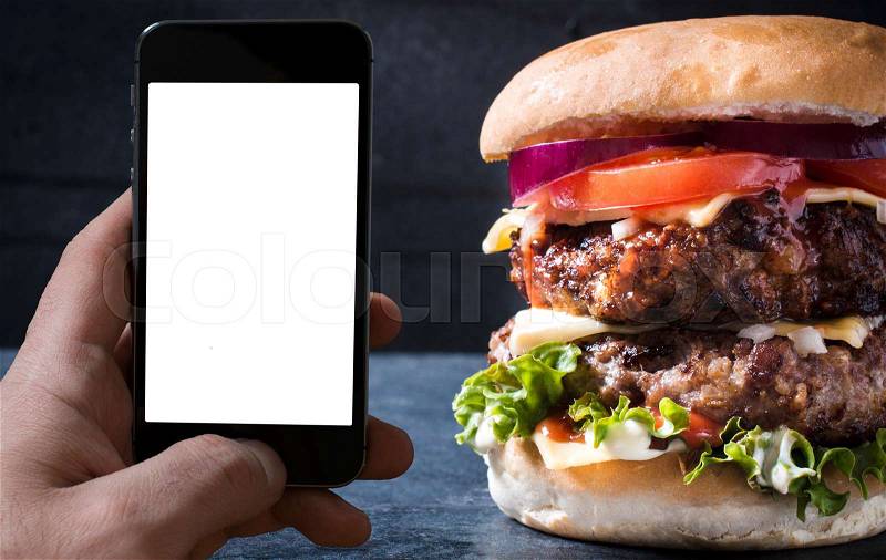Blank screen on mobile phone and big double cheeseburger,take away food order concept, stock photo