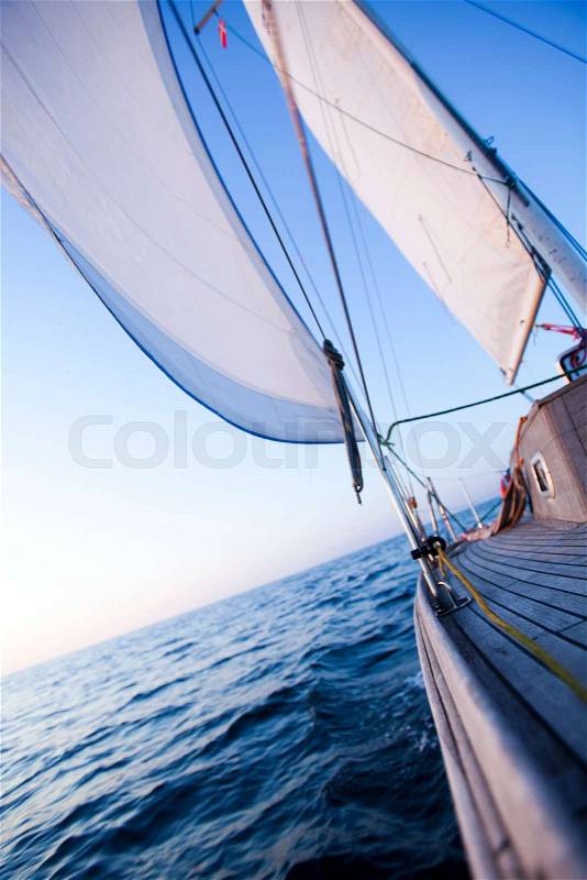 Large winch with line wrapped around and set sail in background, stock photo