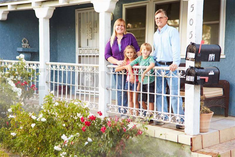Portrait Of Family Standing On Porch Of Suburban Home, stock photo