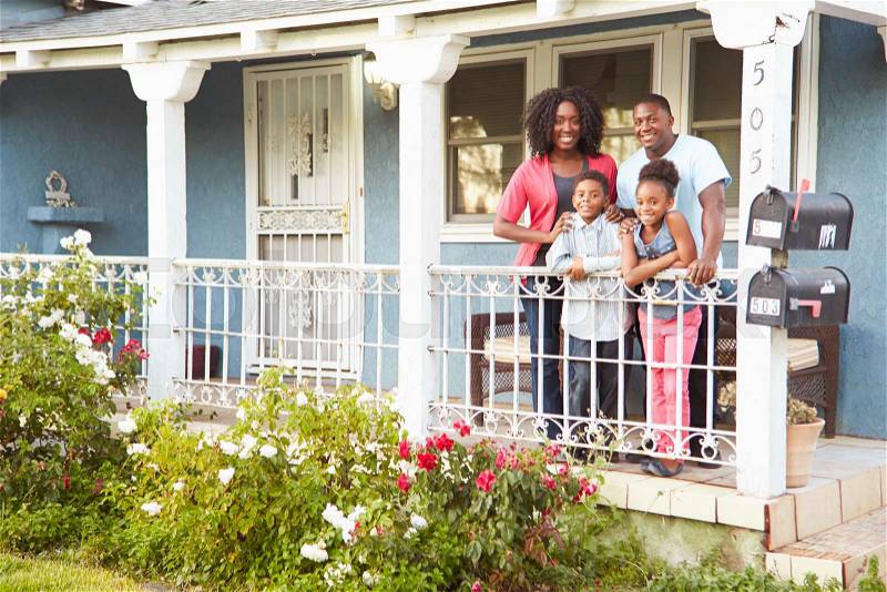 Portrait Of Family Standing On Porch Of Suburban Home, stock photo