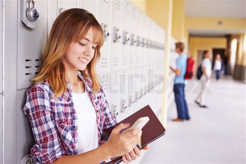 Female High School Student By Lockers Using Mobile Phone, stock photo