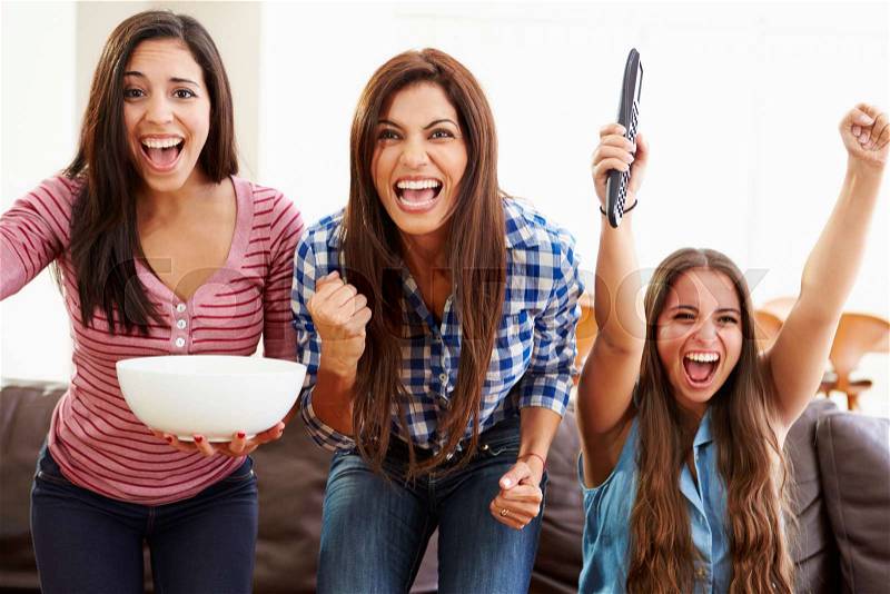 Group Of Women Sitting On Sofa Watching Sport Together, stock photo