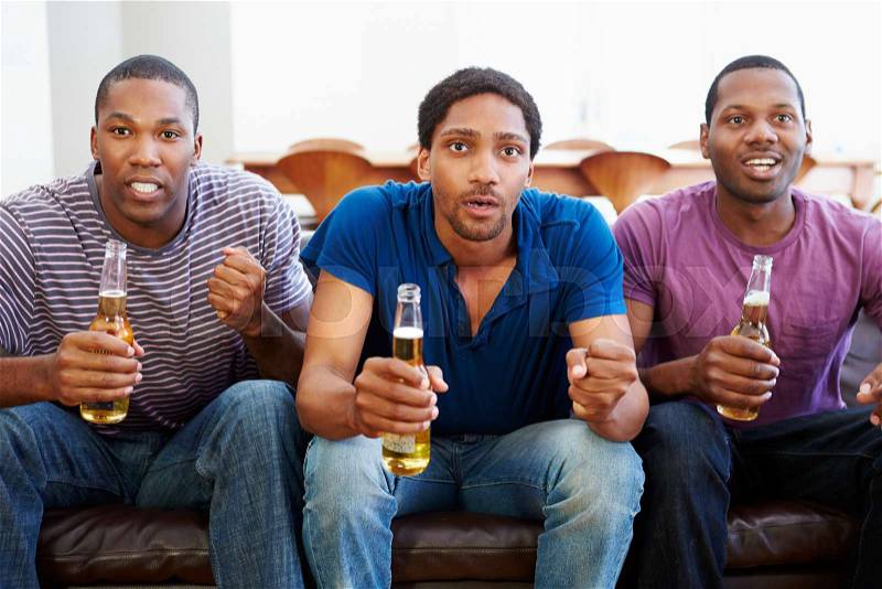 Group Of Men Sitting On Sofa Watching TV Together, stock photo