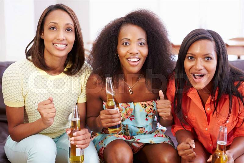Group Of Women Sitting On Sofa Watching TV Together, stock photo