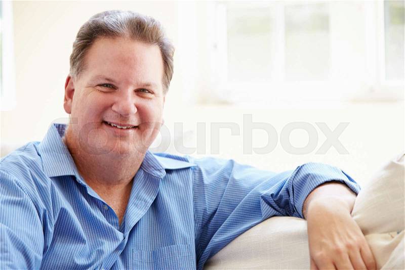 Portrait Of Overweight Man Sitting On Sofa, stock photo