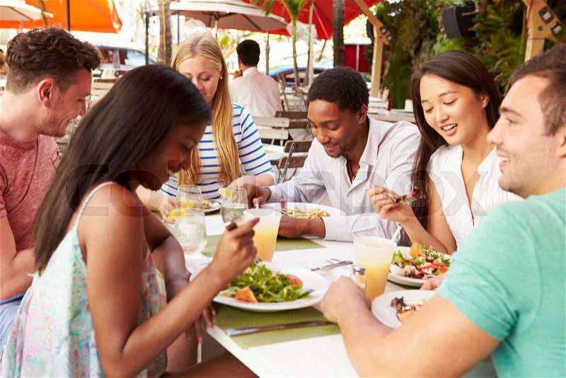 Group Of Friends Enjoying Lunch In Outdoor Restaurant, stock photo